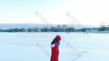 冬天，穿着红色羽绒服的女孩在无人机旁飞来飞去。 女人会下雪